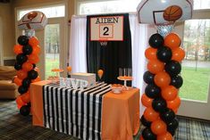 an orange and black basketball themed birthday party with balloon decorations, table cloths and balloons