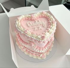 a pink and white heart shaped cake in a box