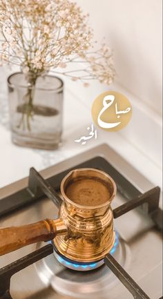 a golden cup sitting on top of a burner next to a vase with flowers