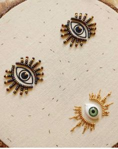 three different types of eye brooches on a piece of cloth