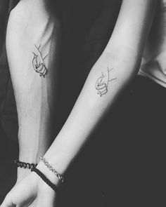 two people holding hands with tattoos on their arms