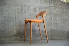 a wooden chair sitting in front of a cement wall