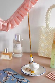 a small white bird sitting on top of a table next to perfume bottles and an umbrella