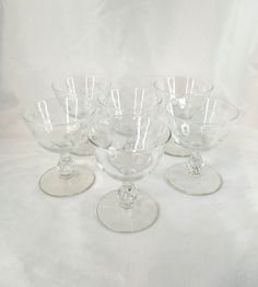 five clear glass bowls on a white tablecloth with one empty bowl in the middle