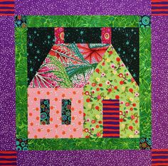 a quilted wall hanging on the side of a building with green and pink accents