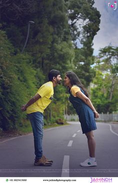 a man and woman standing on the side of a road with trees in the background