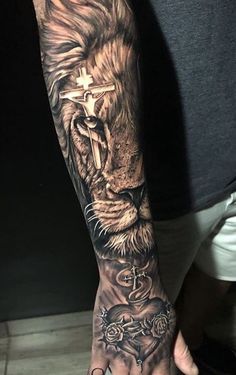 a man's arm with a lion and cross tattoo on the left side of his hand