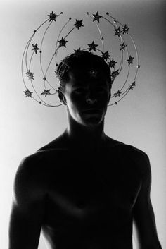 black and white photograph of a man with stars on his head in front of him