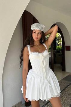 a woman in a white dress and hat posing for the camera