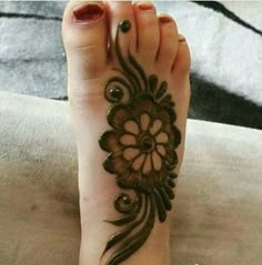 a woman's foot with hennap and flower design on it, sitting on a bed