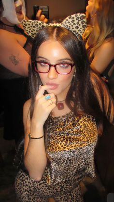 a woman with glasses is brushing her teeth in front of other people at a party