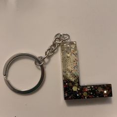 the letter l is made out of glitter and has a metal keychain attached to it