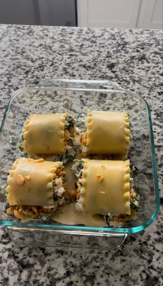 four ravioli with cheese and spinach in a glass dish on a granite countertop