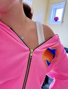 a woman wearing a pink jacket with a rainbow logo on it