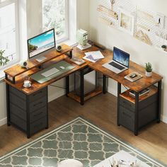 a computer desk with a laptop on top of it next to a rug and window