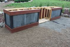 two wooden planters sitting next to each other on top of a dirt field with grass and rocks