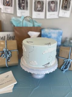 a blue table topped with a cake covered in white frosting and flying kites