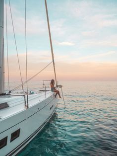 a man sitting on the bow of a sailboat in the ocean at sunset or sunrise