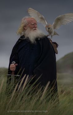 an old man with long white hair holding a bird on his shoulder