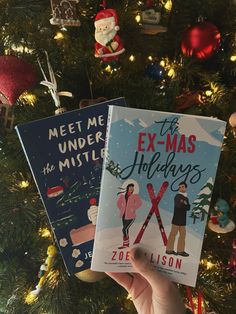 two children's books in front of a christmas tree