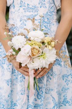 a woman in a blue and white dress holding a bouquet of flowers with her hands