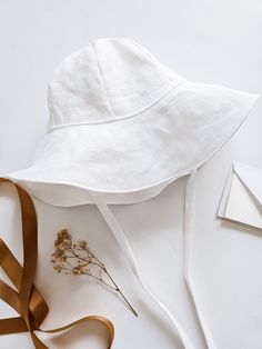 This floppy brim, white linen, spring, summer, or travel baby sunhat is made to keep the sun off your child's face in the summer sunshine. The perfect keepsake accessory for a spring wedding, family vacation, or as a beach hat. A thoughtful newborn baby gift for your new grandbaby or Mother's day, this sun protective hat comes in sizes for infants, babies, and toddlers. Handmade in Utah, USA by me. Size Chart: Please double check sizing before placing your order. (If you would like a little grow White Bucket Sun Hat For Beach, White Bucket Hat For The Beach, White Wide Brim Bucket Hat For Beach Season, White Wide Brim Bucket Hat For Beach, White Bucket Sun Hat For Summer, Adjustable White Summer Hats, White Cotton Sun Hat With Short Brim, White Adjustable Hats For Summer, Summer White Adjustable Hats