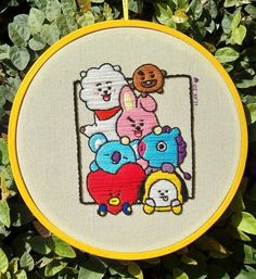 a cross stitch pattern with an image of several cartoon characters on it, in front of some green leaves