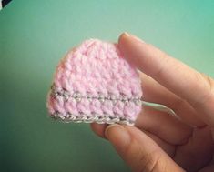 a hand holding a small crocheted pink heart