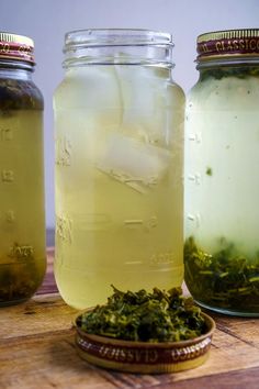 three jars filled with green liquid sitting on top of a wooden table next to each other