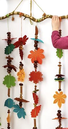 a child's hand is holding onto a wind chime that has leaves on it