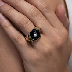 a close up of a person's hand wearing a black and gold ring with a skull on it