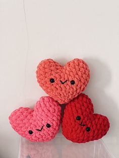 three crocheted hearts sitting next to each other on top of a plastic container