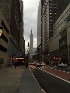 people are walking on the sidewalk in front of tall buildings and traffic lights at dusk