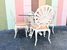 there is a table and chairs that are sitting outside on the pavement in front of a colorful wall