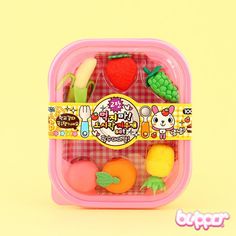 a plastic container filled with assorted fruits and veggies on top of a yellow background