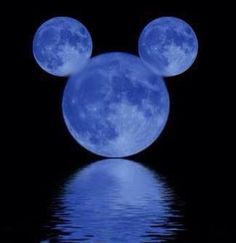 a mickey mouse head with the moon in the sky above it and water reflecting on the ground