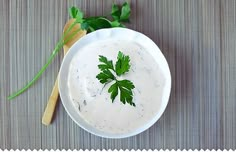 a white bowl filled with dip and parsley on top of a striped tablecloth