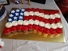 an american flag cake on a table with red, white and blue cupcakes