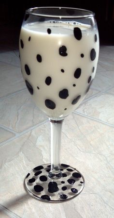 a glass filled with milk sitting on top of a tile floor covered in black and white dots