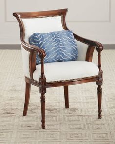 a chair with a blue pillow on top of it in front of a white wall