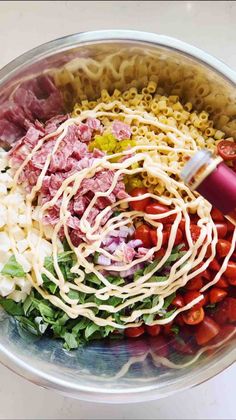 a bowl filled with pasta, meat and veggies on top of a table