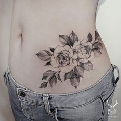 a woman's stomach with flowers and leaves on the side, in black and white