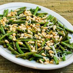 a white plate topped with green beans and pine nuts