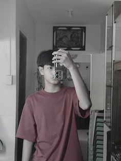 a young man taking a selfie in the mirror with an old camera on his head