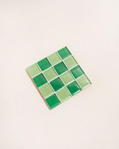 a green and white square tile on a white surface with no one in the photo