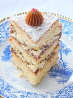 a stack of cake sitting on top of a blue and white plate covered in powdered sugar