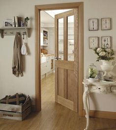 a wooden door in a white room with pictures on the wall and a table next to it