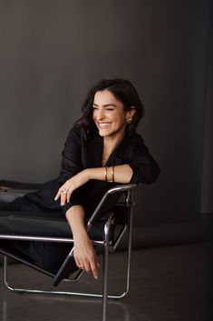 a woman sitting in a chair smiling for the camera