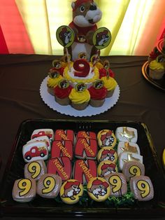 a table topped with cupcakes and cakes covered in frosting next to a stuffed animal