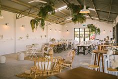 tables and chairs are set up in a large room with plants hanging from the ceiling